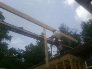 Carpenter setting a ridge beam over a new addition frame — Ice Dam Removal by Roofing Brothers in Iberia