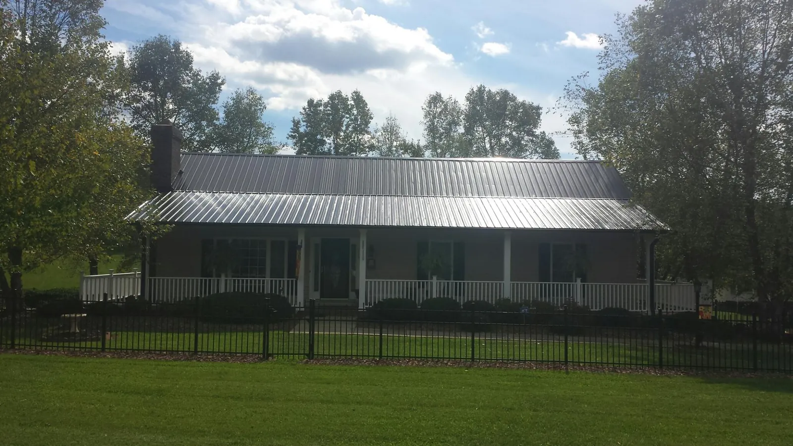 Gray metal roof on a brick ranch with a full width front porch — Gutter Guard Installation work by our crew in Iberia