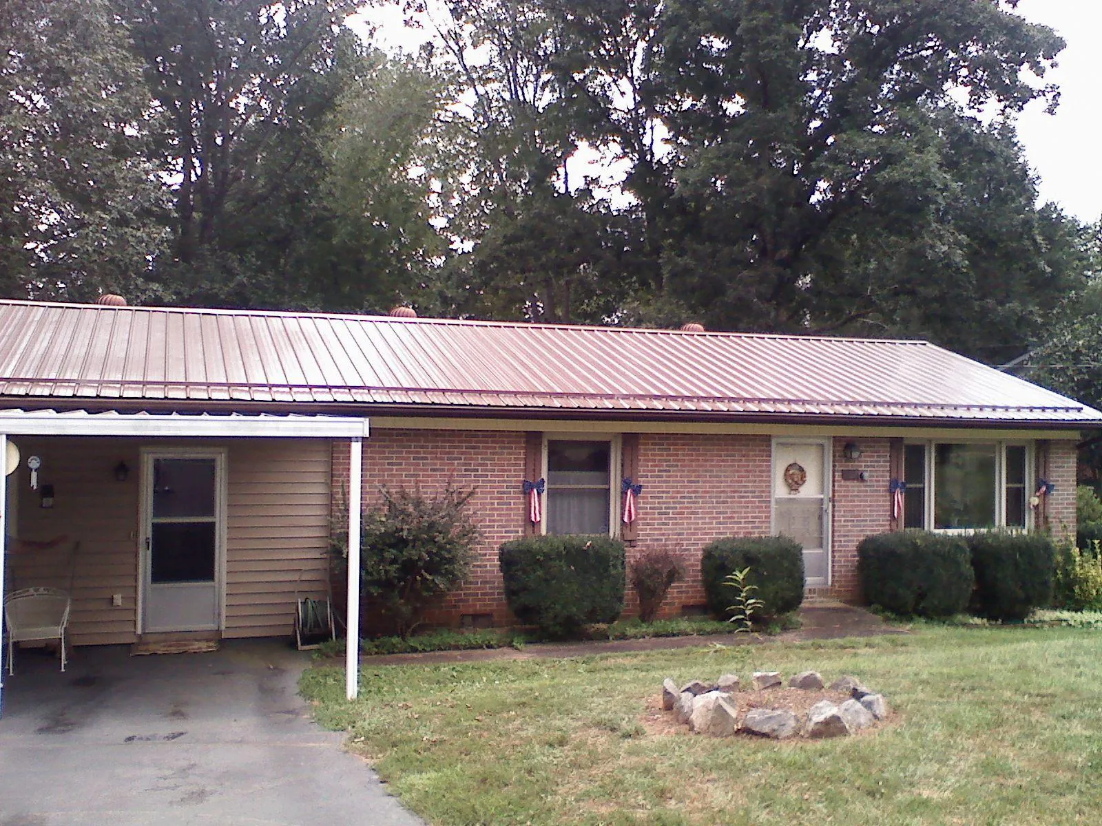 Bronze metal roof and carport on a brick ranch home — Roof Repair work by our crew in Iberia